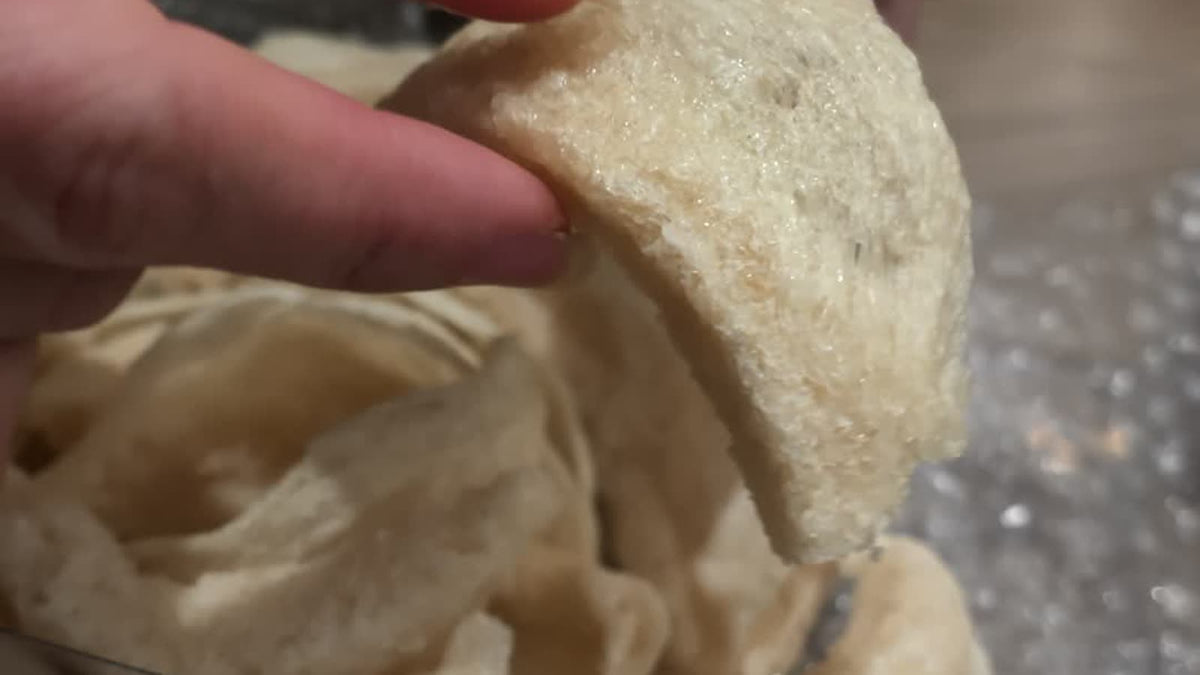 Close-up of a hand pulling apart a piece of fake bird's nest at the Fosetter counter to show its texture.