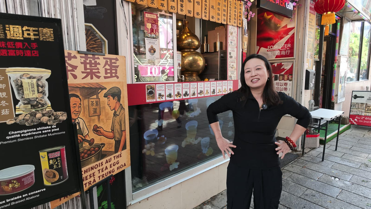 Carmen smiling outside Fosetter beside the shop's anniversary sign and tea egg poster.