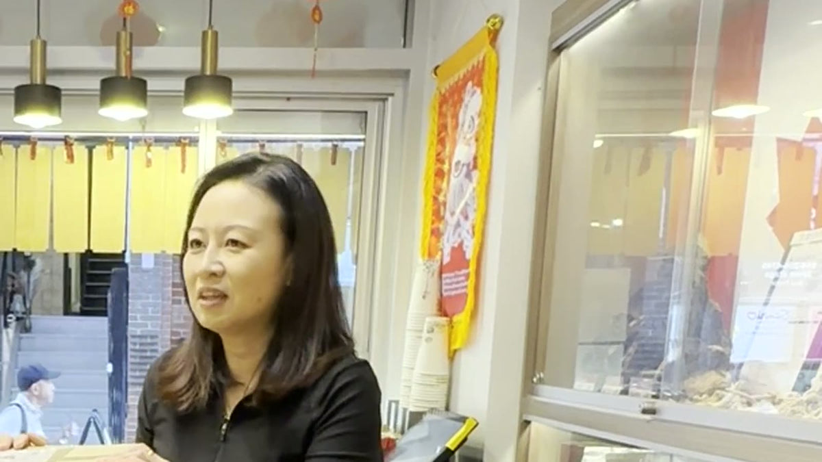 Talking by the counter inside Fosetter, with red lanterns and a lion dance banner in the background.